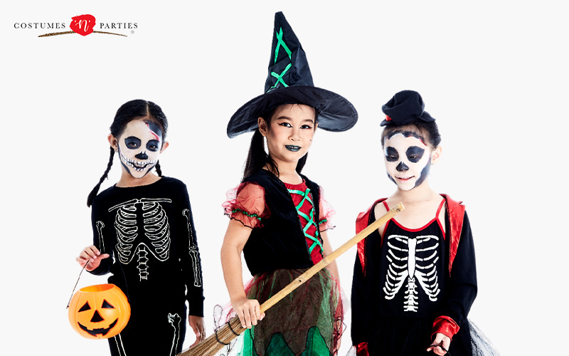 Children wearing skeleton and witch Halloween costumes.